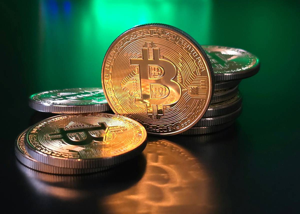 Business owner reviewing extortion insurance policy while laptop displays Cryptocurrency Payments screen